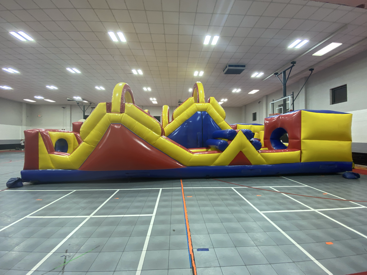 A large inflatable obstacle course set up inside a gym.